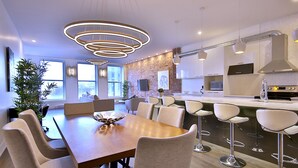 Une cuisine moderne avec une table à manger en bois, des tabourets de bar et des luminaires suspendus.
