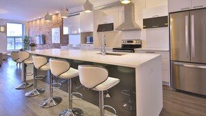 Une cuisine moderne dotée d’un îlot central, d’appareils électroménagers en acier inoxydable et de tabourets de bar.