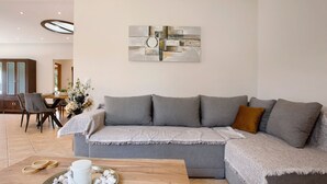 Ett modernt vardagsrum med en grå soffa, ett soffbord i trä och ett abstrakt konstverk som hänger på väggen.