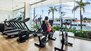 Ginásio com equipamento de exercícios e vista para uma marina.