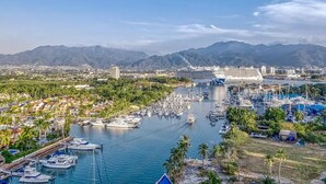 Uma marina com barcos, um cruzeiro e montanhas ao fundo.