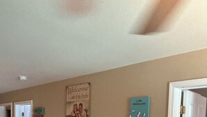 Un pasillo con un cartel de bienvenida, un reloj y una mesa decorativa con un jarrón.