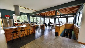 A modern kitchen with a large island, bar stools, and a view of the outdoors. - Suite Flotante: glass carpet floor and magical views (Oaxaca de Juárez)