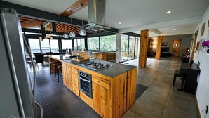 A modern kitchen with a central island, wooden cabinetry, and a large window providing a view of the outdoors. - Suite Flotante: glass carpet floor and magical views (Oaxaca de Juárez)