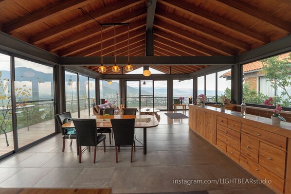 A spacious dining area with a high ceiling and large windows offering a view of the mountains.