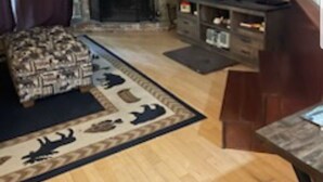 Una sala de estar con chimenea de piedra, televisor de pantalla plana y alfombra estampada.