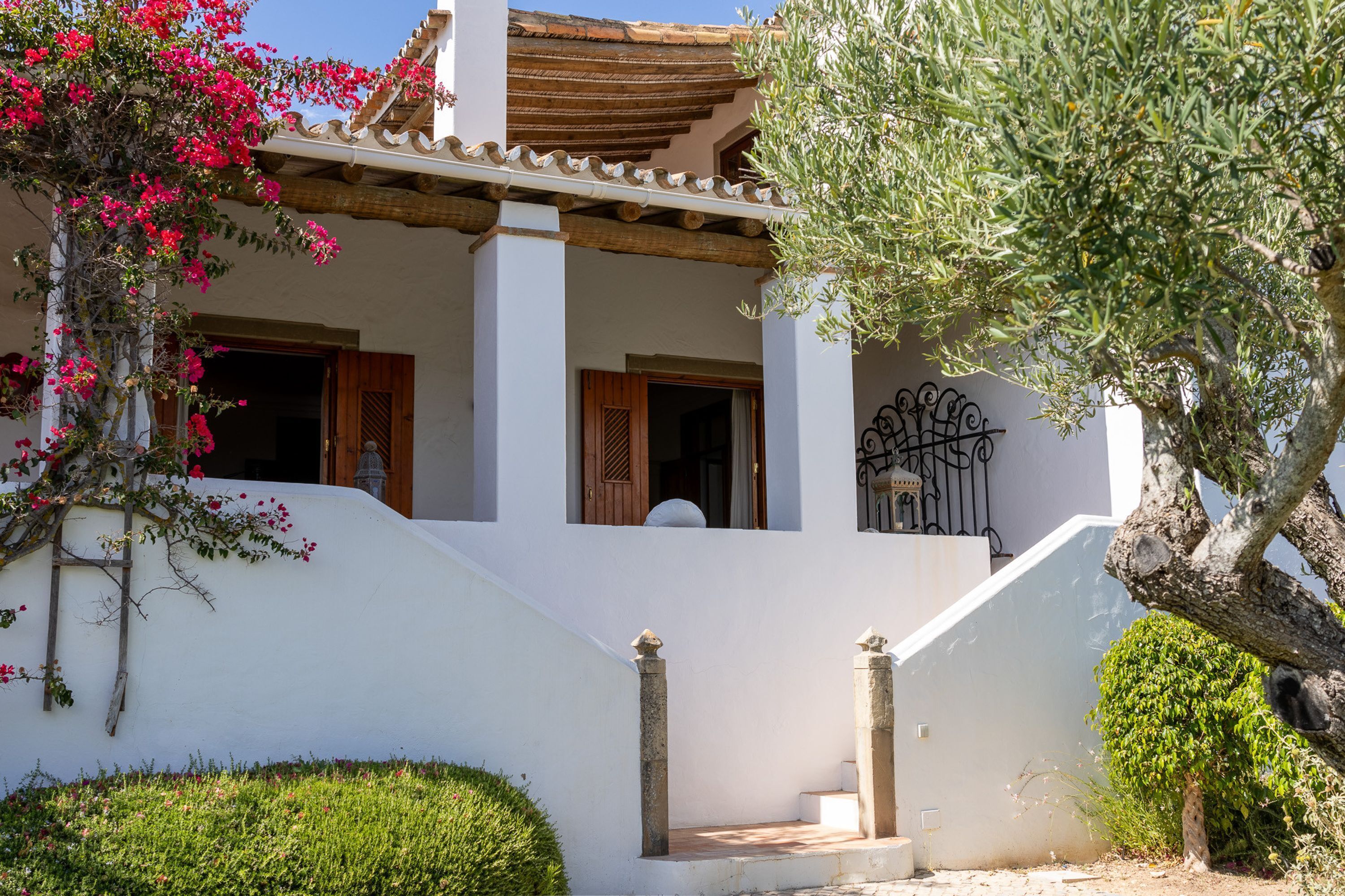 A white building with a tiled roof, a staircase, and a small balcony.