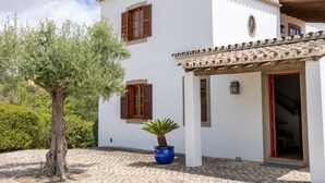 A white building with a tiled roof, a potted plant, and a door with a red frame. - Almancil Sea and Countryside Secluded Villa (Loulé)
