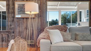Un salon chaleureux avec un mur en bois, une grande fenêtre, un canapé et un lampadaire.