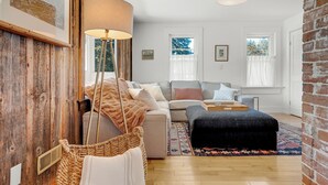 Un salon confortable avec un canapé, un pouf et une lampe.
