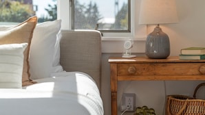 Une chambre à coucher avec un lit, une table de chevet avec une lampe, une fenêtre et une vue sur l’extérieur.