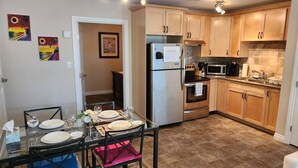 A compact kitchen with wooden cabinets, a stainless steel refrigerator, a microwave, and an oven.