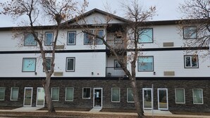 A multi-story building with a flat roof, multiple windows, and a stone facade.
