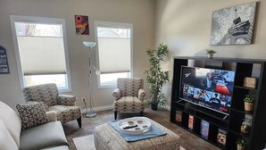 A living room with a sofa, two patterned armchairs, a coffee table, a TV, and a bookshelf.