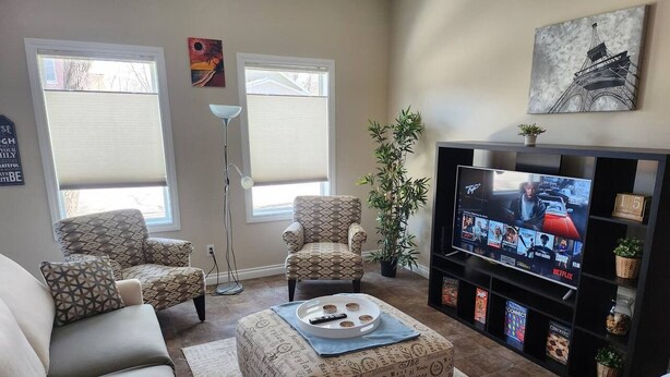 A living room with a sofa, armchairs, a coffee table, a television, and a bookshelf.