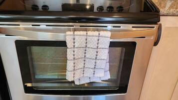 A kitchen with a stainless steel stove and oven, a towel hanging inside the oven, and a knife rack on the countertop.