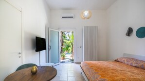 Une pièce comprenant un lit, une table, une chaise, un téléviseur et une porte donnant sur un balcon.