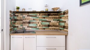 Une cuisine avec un mur de protection en bois derrière l’évier, un évier et des armoires blanches.
