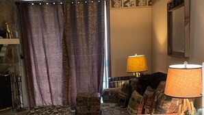 Una sala de estar acogedora con un sofá estampado, una mesa de comedor de madera y una lámpara.