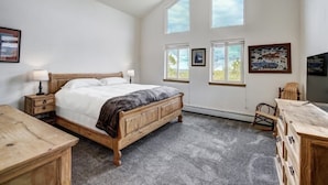 Een slaapkamer met een groot bed, een houten dressoir en een plafondventilator.
