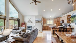 Een ruime woonkamer met een grote bank, een houten eettafel en een keuken met houten kasten en een groot eiland.
