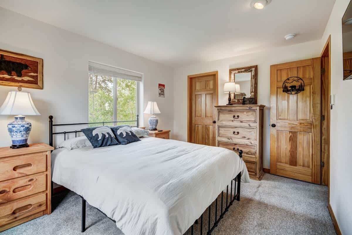 A bedroom with a bed, wooden dresser, and a mirror.