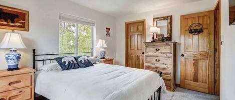 A bedroom with a bed, wooden dresser, and a mirror.
