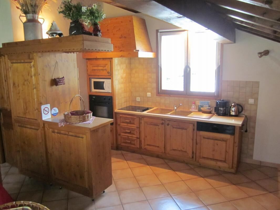 A kitchen with wooden cabinets, a central island, a window, and a tiled floor.