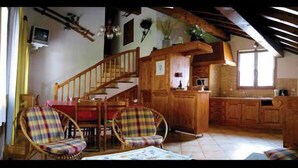 A rustic interior with a wooden staircase, a kitchen, and plaid-patterned furniture. - GITE LA GRANDE ROCHE (CHAMPAGNY EN VANOISE)
