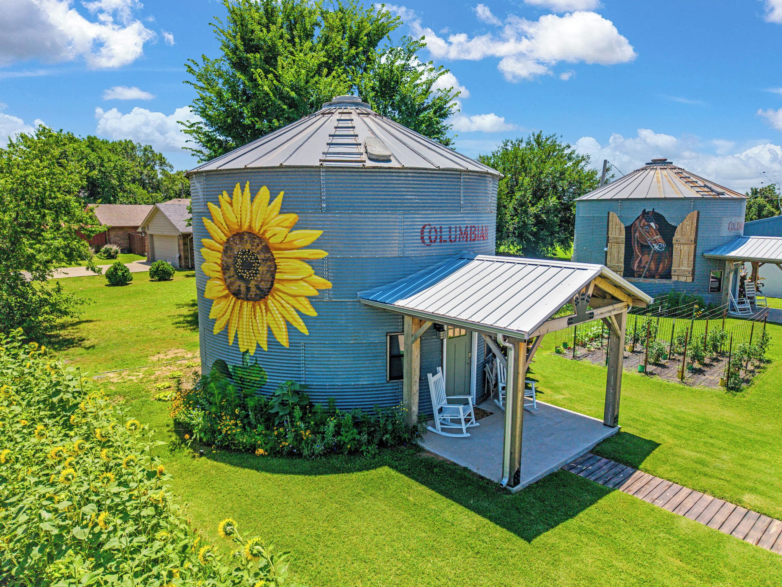 A large cylindrical building with a sunflower mural and a covered porch.