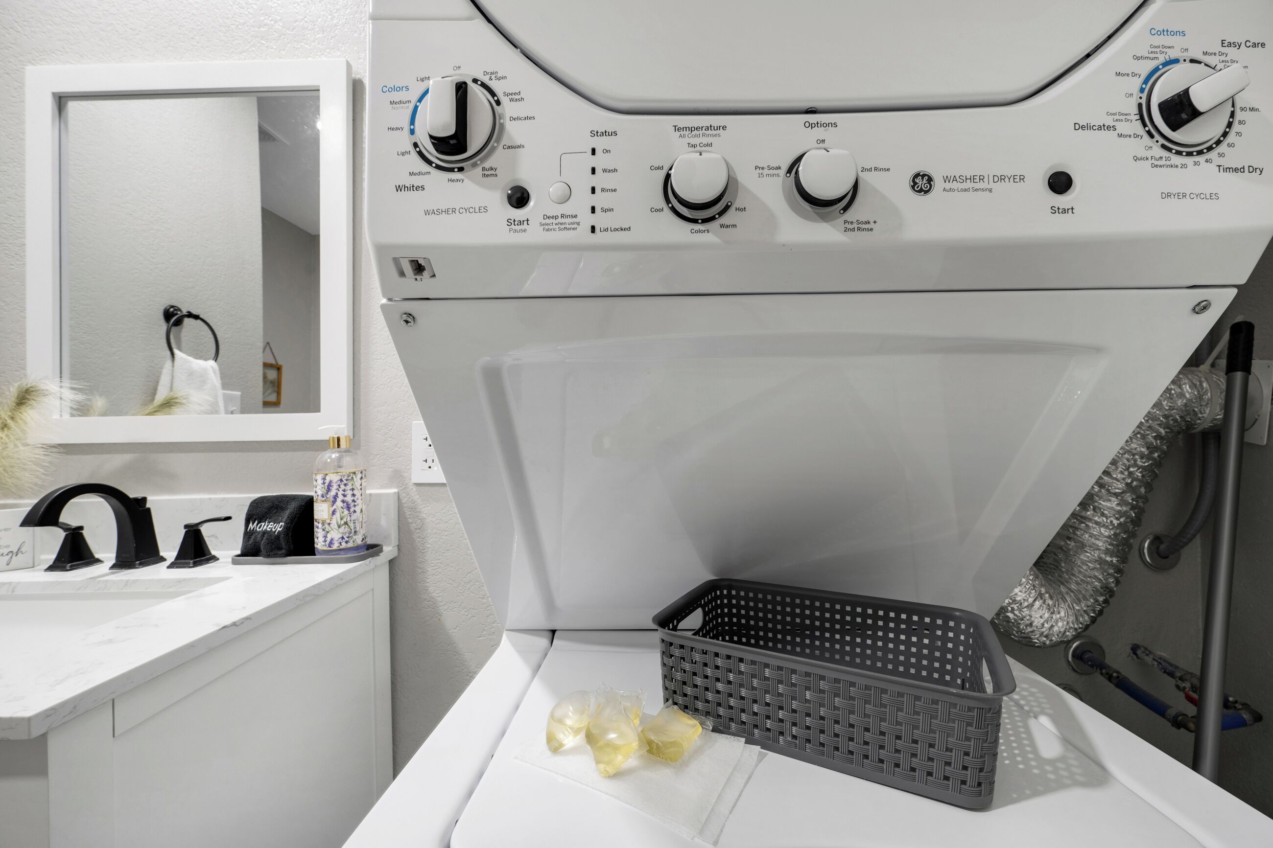 A modern laundry area with a washing machine, a sink, and a basket.