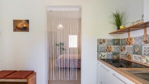 Ein Zimmer mit einem Bett, einer Bank, einer Küche inklusive Spüle und einer Wand mit Dekoration.