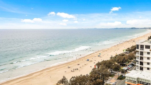A beach with a clear view of the ocean and a building with multiple floors and balconies. - Front Row to the Tide at Imperial Surf (Gold Coast)