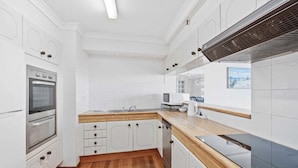 A modern kitchen with white cabinetry, a wooden countertop, and a built-in oven. - Front Row to the Tide at Imperial Surf (Gold Coast)