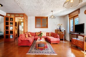 A living room with a sectional sofa, a coffee table, a television, and a large window.