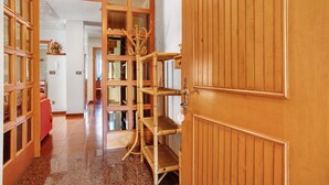 A hallway with wooden paneling, a door with a brass handle, and a wicker shelf unit. - Apartment 'Casa Lella Clemy' with Mountain View, Balcony and Wi-Fi (Aymavilles)