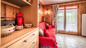 A wooden interior with a sofa, a red chair, a small table, and baskets. - Apartment 'Appartement Les Oursons' with Mountain View, Balcony and Wi-Fi (Morillon)