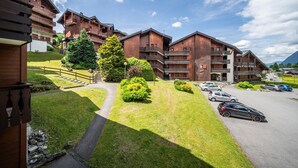 A hotel with wooden balconies, a parking area, and a clear sky. - Apartment 'Appartement Les Oursons' with Mountain View, Balcony and Wi-Fi (Morillon)
