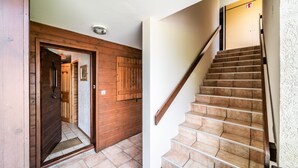 A wooden door leading to a hallway, a staircase with a handrail, and a fire exit sign. - Apartment 'Appartement Les Oursons' with Mountain View, Balcony and Wi-Fi (Morillon)