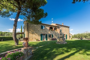 A stone building with a well-maintained lawn and a statue in the center.