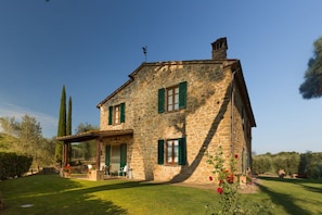 A stone house with a covered porch and a well-maintained lawn.