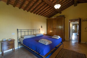 A bedroom with a bed, wooden wardrobe, and a nightstand.