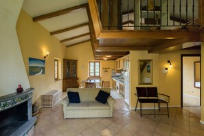 A spacious living area with a sofa, a chair, a fireplace, and a staircase.