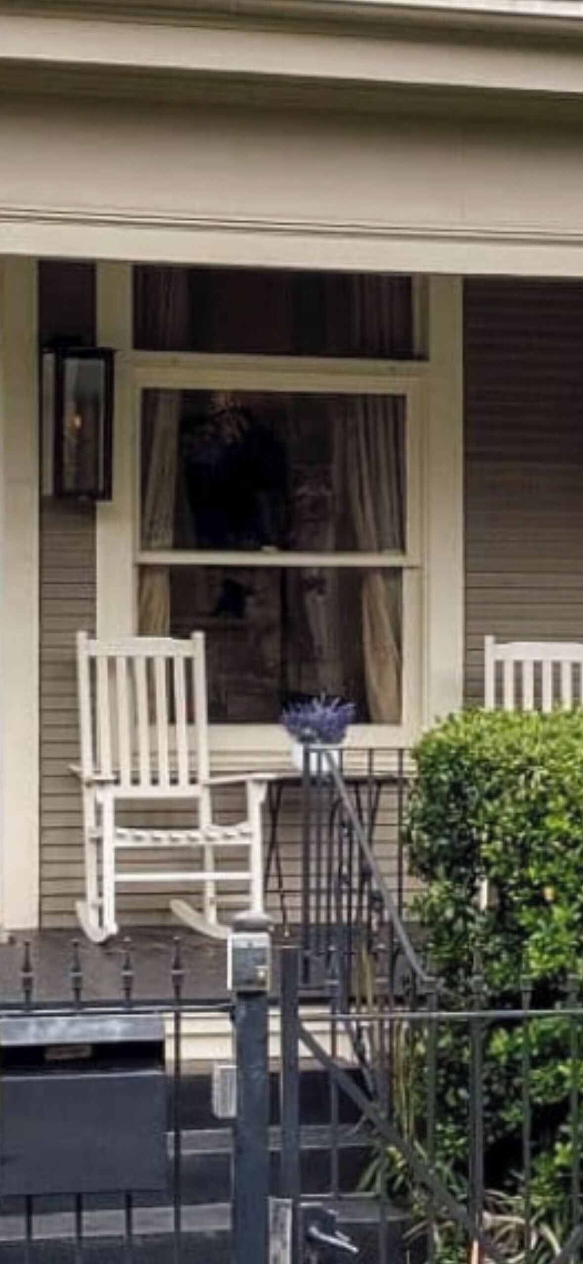 A house with a porch, a chair, a table, and a potted plant.