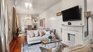 Una sala de estar con sofá, mesa de centro, chimenea, televisión y objetos decorativos.