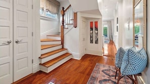 Un pasillo amplio con escaleras de madera, puertas blancas y un tapete estampado.
