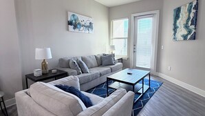 A modern living room with a grey sofa, a coffee table, and a blue rug. - POOL VIEW/DOWNTOWN DALLAS/MEDICAL DISTRICT/DALLAS LOVE FIELD (Dallas)
