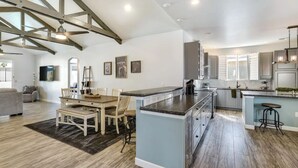 Een ruime keuken met een groot eiland, houten balken in het zicht en een zithoek met een tafel en stoelen.