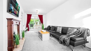 A modern living room with a black leather sofa, a wooden coffee table, and a fireplace. - Stunning 2-bed House in Birmingham (Birmingham)