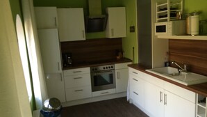 A compact kitchen with white cabinets, a built-in oven, and a wooden countertop. - Vacation apartment in the tower  (Lehmkuhlen)